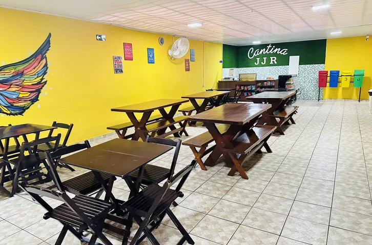 Cantina do Colégio JJR com mesas de madeira, mural colorido e balcão de atendimento
