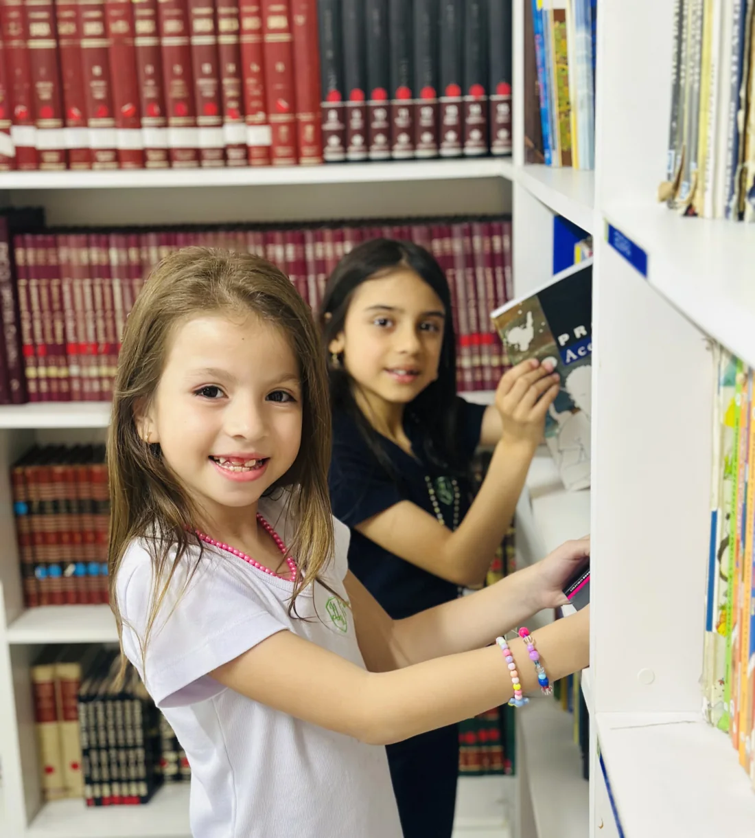 Duas estudantes do Colégio JJR consultando livros na biblioteca