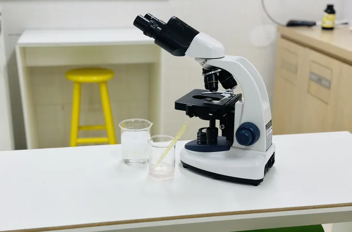 Microscópio e béqueres sobre a bancada do laboratório de ciências do Colégio JJR